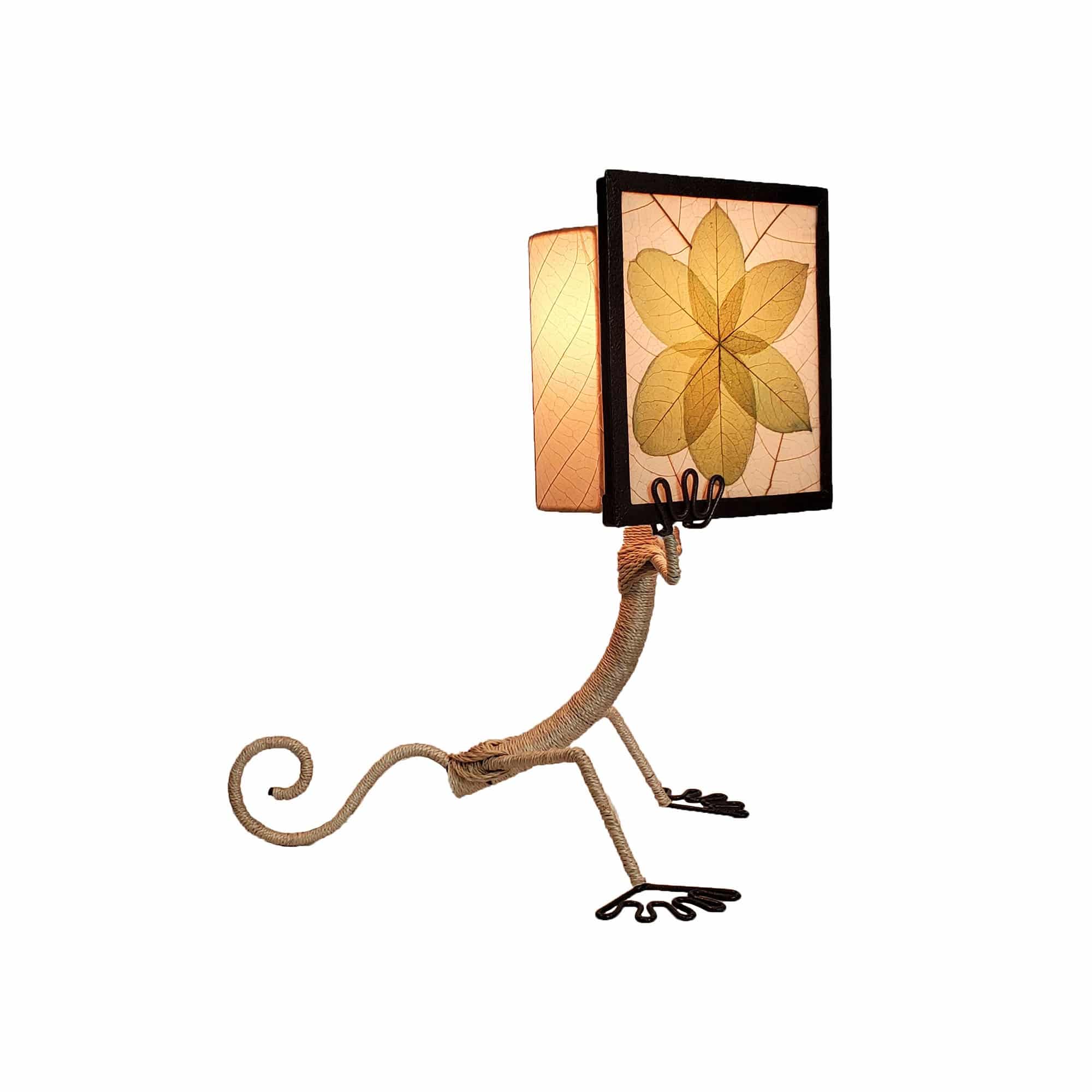 Crafted by the artisans of Eangee Home Design, the Enlightened Gecko Table Lamp in green against a clean backdrop, featuring fossilized cocoa leaf shade, guyabano leaf shade, abaca rope accents, wrought iron frame, handcrafted.