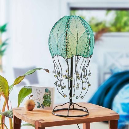 Jellyfish?inspired table lamp crafted by Eangee Home Design draped in sea blue cocoa?leaf panels that flow like tentacles; underwater feel enhanced as cozy light glows through translucent cocoa leaves; handcrafted sustainably by fair?trade artisans