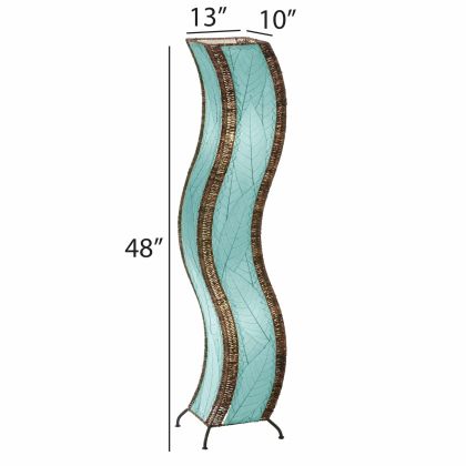 The Eangee Home Design Wave Large Floor Lamp Sea Blue (item #457 l sb), with brown accents, stands on a wooden platform in a modern room beside a green plant and minimalist shelves, adding soothing motion and calm to the space.