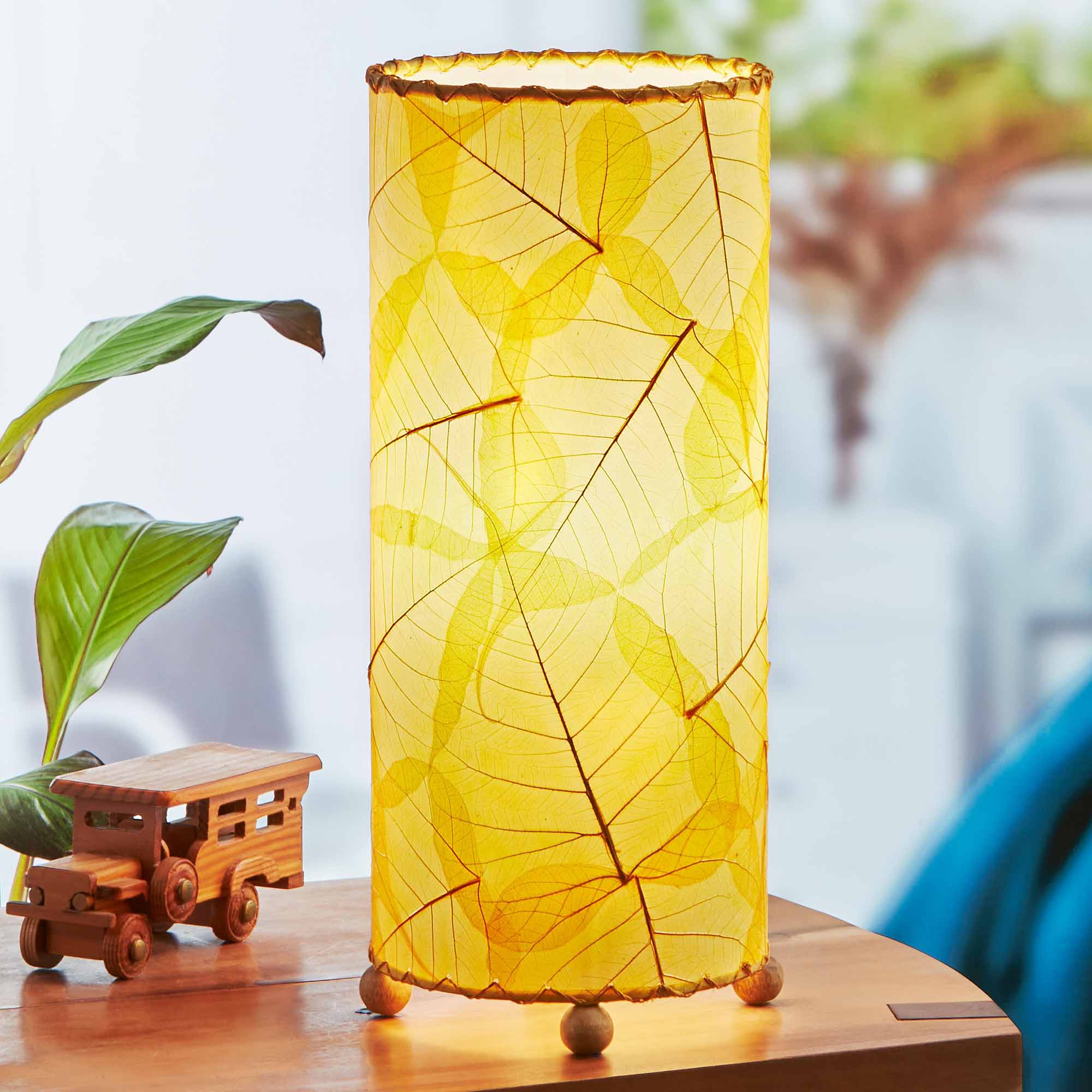 In a modern interior with earth tones, crafted by the artisans of Eangee Home Design, the Banyan Table Lamp in orange stands gracefully, featuring wrought iron frame, eco friendly, adding warmth and character to the space.