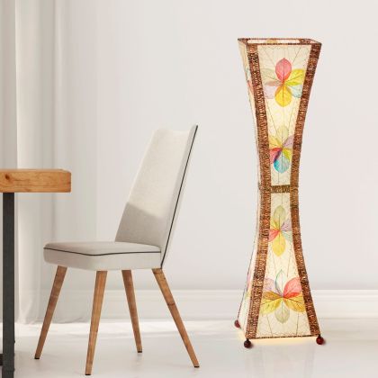 In a softly lit reading nook, crafted by the artisans of Eangee Home Design, the Hourglass Large Floor Lamp in multi color stands gracefully, featuring jackfruit leaf panels, abaca rope accents, fair trade, eco friendly, sustainably sourced, adding warmth and character to the space.