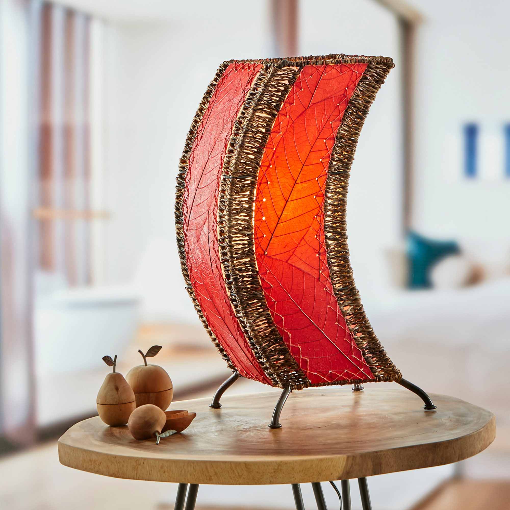 In a modern interior with earth tones, crafted by the artisans of Eangee Home Design, the C Shape Table Lamp in red stands gracefully, featuring fossilized cocoa leaf shade, abaca rope accents, fair trade, handcrafted, adding warmth and character to the space.