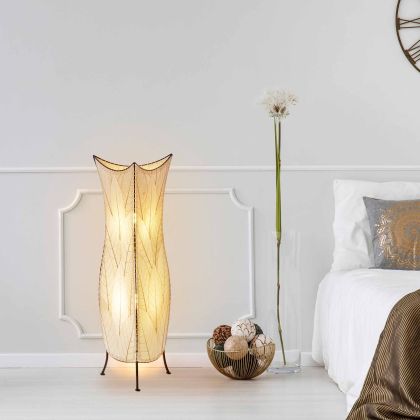 In a quiet bedside corner, crafted by the artisans of Eangee Home Design, the Flowerbud Large Floor Lamp in natural stands gracefully, featuring fossilized cocoa leaf shade, adding warmth and character to the space.