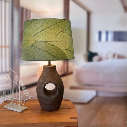 Crafted by the artisans of Eangee Home Design, the 16 Inch Tapered Drum Shade in green against a clean backdrop, featuring fossilized cocoa leaf shade, wrought iron frame, fair trade, sustainably sourced, handcrafted.