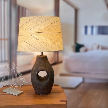 Crafted by the artisans of Eangee Home Design, the 16 Inch Tapered Drum Shade in natural against a clean backdrop, featuring fossilized cocoa leaf shade, wrought iron frame, fair trade, sustainably sourced, handcrafted.