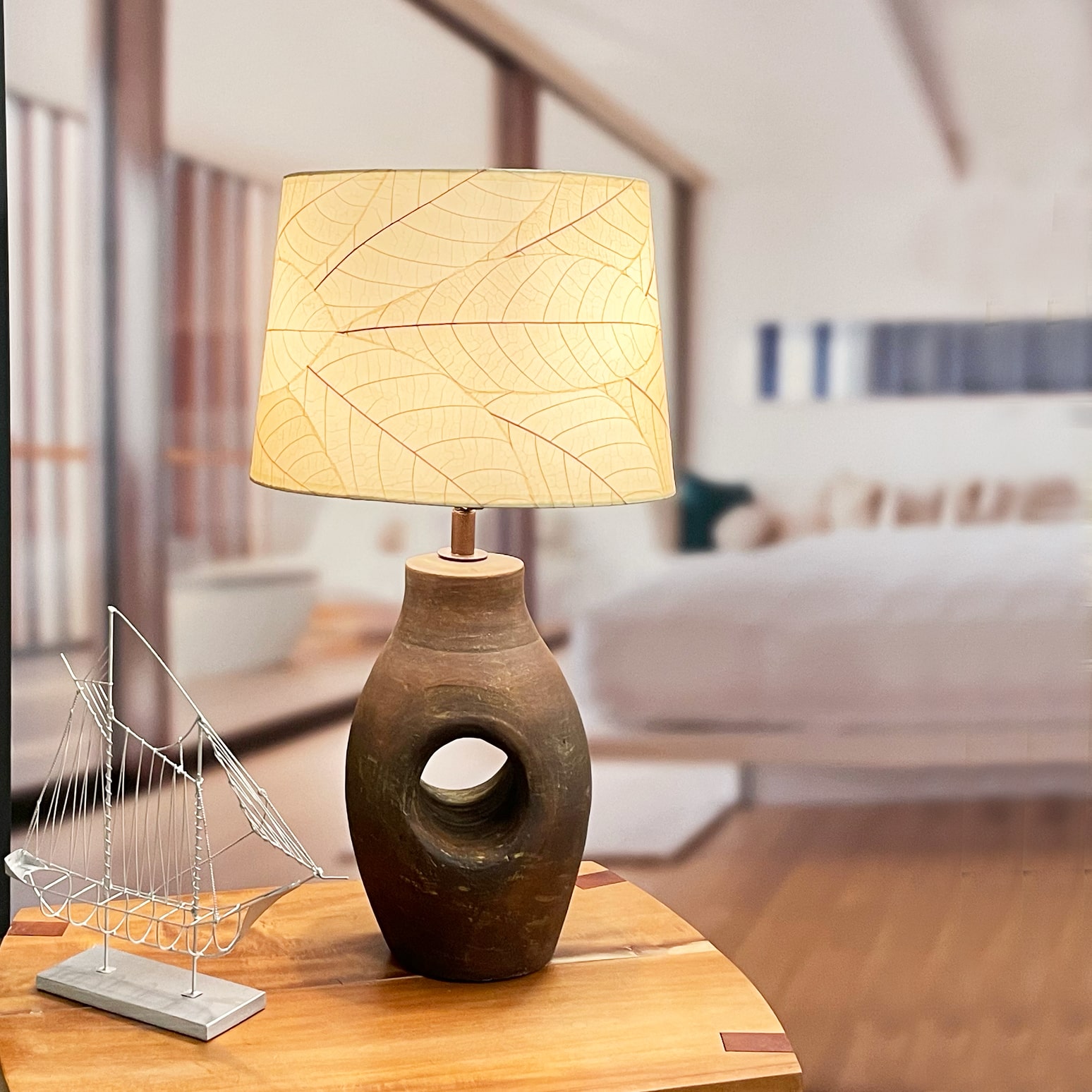 In a sun drenched entryway, crafted by the artisans of Eangee Home Design, the 14 Inch Tapered Drum Shade in natural stands gracefully, featuring fossilized cocoa leaf shade, wrought iron frame, fair trade, eco friendly, sustainably sourced, handcrafted, adding warmth and character to the space.