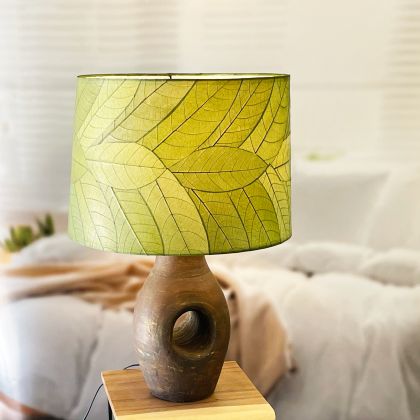 In a sun drenched entryway, crafted by the artisans of Eangee Home Design, the 18 Inch Tapered Drum Shade in green stands gracefully, featuring fossilized cocoa leaf shade, wrought iron frame, eco friendly, sustainably sourced, adding warmth and character to the space.