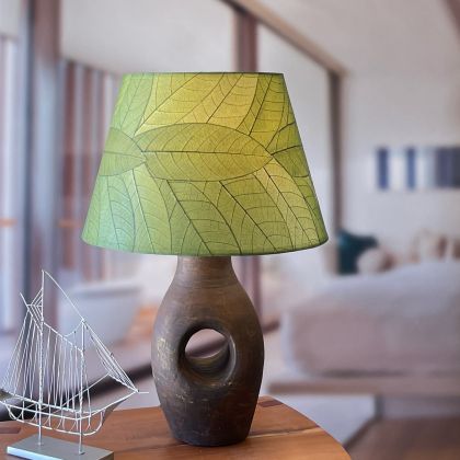 In a minimalist loft with natural textures, crafted by the artisans of Eangee Home Design, the 18 Inch British Empire Shade in green stands gracefully, featuring fossilized cocoa leaf shade, wrought iron frame, eco friendly, sustainably sourced, adding warmth and character to the space.