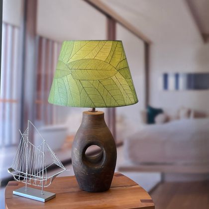 In a coastal inspired living room, crafted by the artisans of Eangee Home Design, the 16 Inch British Empire Shade Green Color in  stands gracefully, featuring fossilized cocoa leaf shade, wrought iron frame, fair trade, eco friendly, sustainably sourced, adding warmth and character to the space.