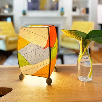 On a end table beside a sofa, the Mini Square Cocoa Leaf Table crafted by the artisans of Eangee Home Design Lamp in multi color finish by Eangee Home Design glows softly, its fossilized cocoa leaf panels, wrought iron frame, and hand placed natural leaves bringing it's the warm, inviting glow that draws you in first.