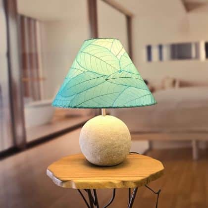 In a softly lit reading nook, crafted by the artisans of Eangee Home Design, the Bell Shade Cocoa in sea blue stands gracefully, featuring fossilized cocoa leaf shade, wrought iron frame, handcrafted, adding warmth and character to the space.