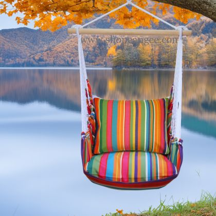 In an outdoor reading nook a multi colored outdoor swing crafted by the artisans of Magnolia Casual called the Swing Set 4 piece Le Jardin Stripe w/ Le Jardin Stripe is displayed featuring 100 percent weather resistant fabric, weather resistant polyester fabric, handcrafted adding comfort and style to the space featuring with a stripe motif.