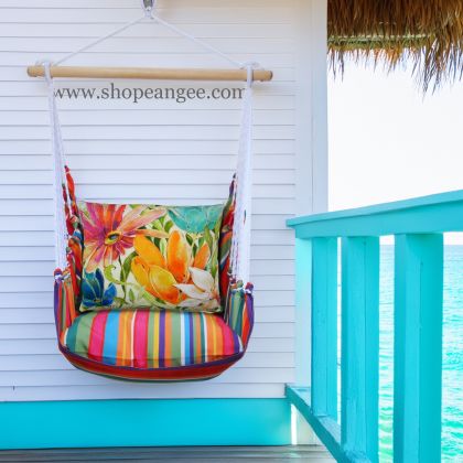 In a shaded porch swing a multi colored outdoor swing crafted by the artisans of Magnolia Casual called the Swing Set 4 piece Le Jardin Stripe w/ Tropical 1 is displayed featuring 100 percent weather resistant fabric, weather resistant polyester fabric, handcrafted adding comfort and style to the space featuring with a stripe motif.