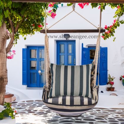 In a cozy garden seating area a multi colored outdoor swing crafted by the artisans of Magnolia Casual called the Swing Set 4 piece Marina Stripe w/ Marina Stripe is displayed featuring 100 percent weather resistant fabric, weather resistant polyester fabric, handcrafted adding comfort and style to the space featuring with a stripe motif.