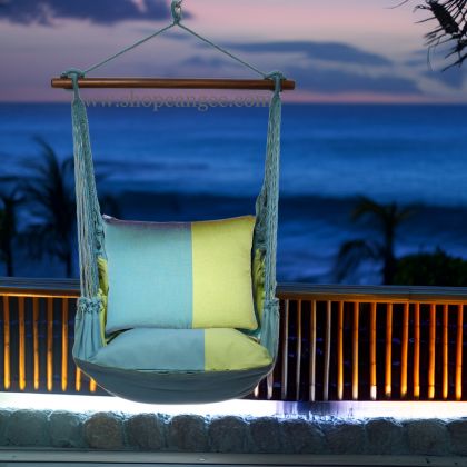 In a cozy garden seating area a multi colored outdoor swing crafted by the artisans of Magnolia Casual called the Swing Set 4 piece Meadow Mist Stripe w/ Meadow Mist Stripe is displayed featuring 100 percent weather resistant fabric, weather resistant polyester fabric, handcrafted, natural materials adding comfort and style to the space featuring with a stripe motif.