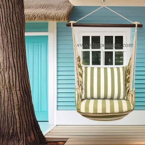 In an outdoor reading nook a multi colored outdoor swing crafted by the artisans of Magnolia Casual called the Swing Set 4 piece Summer Palms Stripe w/ Summer Palms Stripe is displayed featuring 100 percent weather resistant fabric, weather resistant polyester fabric, handcrafted adding comfort and style to the space featuring with a stripe motif.