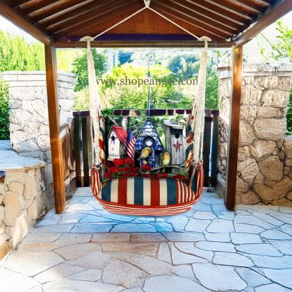 In a poolside chaise a multi colored outdoor swing crafted by the artisans of Magnolia Casual called the Swing Set 4 piece Stars & Stripes w/ Americana Birdhouses is displayed featuring 100 percent weather resistant fabric, weather resistant polyester fabric, handcrafted adding comfort and style to the space featuring with a stripes motif.