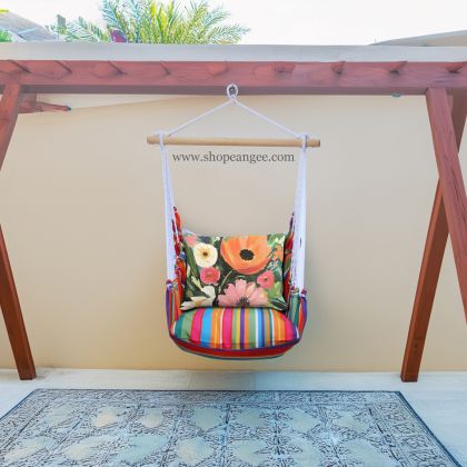 In a sunlit patio lounge a multi colored outdoor swing crafted by the artisans of Magnolia Casual called the Swing Set 4 piece Le Jardin Stripe w/ Spring Fling is displayed featuring 100 percent weather resistant fabric, weather resistant polyester fabric, handcrafted adding comfort and style to the space featuring with a stripe motif.