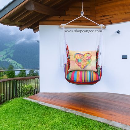 In a poolside chaise a multi colored outdoor swing crafted by the artisans of Magnolia Casual called the Swing Set 4 piece Le Jardin Stripe w/ Colorful Heart is displayed featuring 100 percent weather resistant fabric, weather resistant polyester fabric, handcrafted adding comfort and style to the space featuring with a stripe motif.