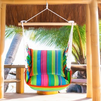 In a sunlit patio lounge a multi colored outdoor swing crafted by the artisans of Magnolia Casual called the Swing Set 4 piece Le Jardin Nouveau w/ Le Jardin Nouveau is displayed featuring 100 percent weather resistant fabric, weather resistant polyester fabric, handcrafted adding comfort and style to the space.