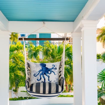 In a coastal inspired deck chair a multi colored outdoor swing crafted by the artisans of Magnolia Casual called the Swing Set 4 piece Marina Stripe w/ Indigo Octopus is displayed featuring 100 percent weather resistant fabric, weather resistant polyester fabric, handcrafted adding comfort and style to the space featuring with a stripe motif.