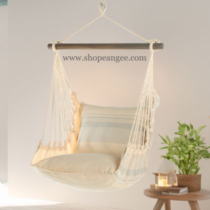 In an outdoor reading nook a multi colored outdoor swing crafted by the artisans of Magnolia Casual called the Swing Set 4 piece Magnolia Stripe w/ Magnolia Stripe is displayed featuring 100 percent weather resistant fabric, weather resistant polyester fabric, handcrafted adding comfort and style to the space featuring with a magnolia motif.