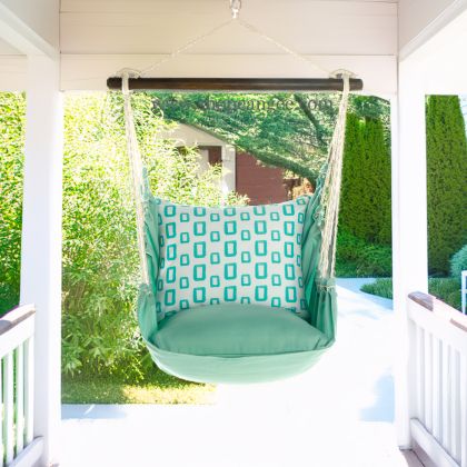 In a cozy garden seating area a green outdoor swing crafted by the artisans of Magnolia Casual called the Swing Set 4 piece Seafoam Green Solid w/ Infinite Frames is displayed featuring 100 percent weather resistant fabric, weather resistant polyester fabric, handcrafted adding comfort and style to the space featuring shades of green.