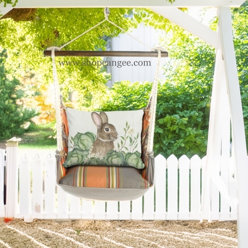 In a sunlit patio lounge a multi colored outdoor swing crafted by the artisans of Magnolia Casual called the Swing Set 4 piece Serene Sunset w/ Rabbit and Cabbages is displayed featuring 100 percent weather resistant fabric, weather resistant polyester fabric, handcrafted adding comfort and style to the space featuring with a rabbit motif.