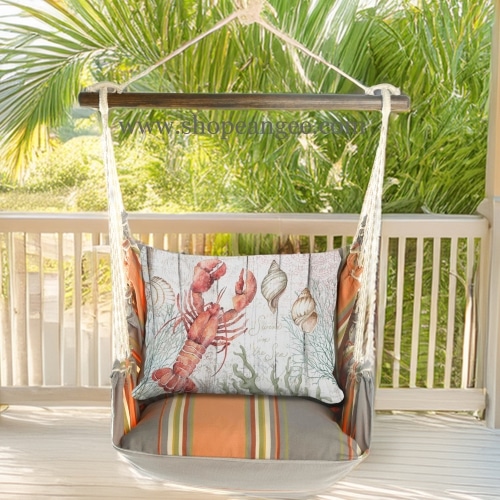 In a shaded porch swing a multi colored outdoor swing crafted by the artisans of Magnolia Casual called the Swing Set 4 piece Serene Sunset w/ Lobster with Seashells is displayed featuring 100 percent weather resistant fabric, weather resistant polyester fabric, handcrafted adding comfort and style to the space featuring with a lobster motif.