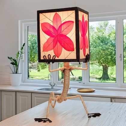 Gecko?shaped table lamp crafted by Eangee Home Design with red fossilized cocoa?leaf panels hand?stitched onto a wrought?iron frame; playful gecko silhouette hugs the shade, and warm light glows across the textured leaf panels; handcrafted sustainably by fair?trade artisans