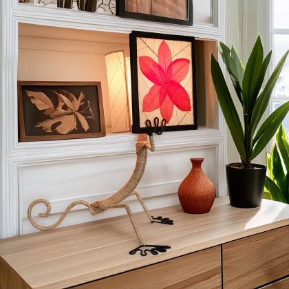 Crafted by the artisans of Eangee Home Design, the Enlightened Gecko Table Lamp in red against a clean backdrop, featuring fossilized cocoa leaf shade, guyabano leaf shade, abaca rope accents, wrought iron frame, handcrafted.