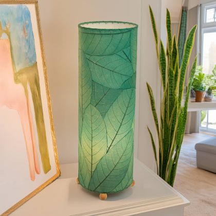 Slim cylinder table lamp crafted by Eangee Home Design in sea blue fossilized cocoa leaves, each panel hand?laminated and stitched; minimalist form offers textural leaf detail while inviting light shines through every vein; artisan?made with renewable materials
