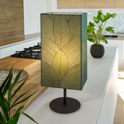 Tall Sequoia?inspired table lamp crafted by Eangee Home Design clad in green fossilized cocoa leaves on a curved wrought?iron frame; towering form echoes tree bark texture, and cozy light shines through translucent cocoa leaves; artisan?made from sustainable materials