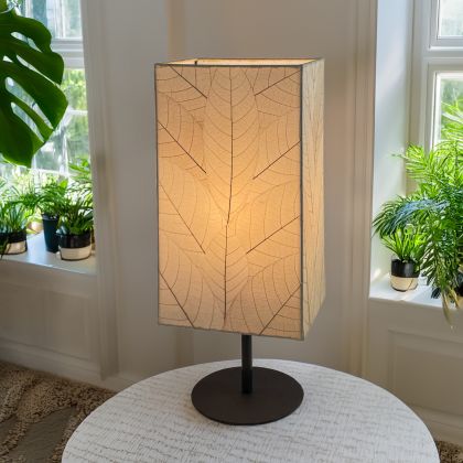 In a modern interior with earth tones, crafted by the artisans of Eangee Home Design, the Sequoia Table Lamp in natural stands gracefully, featuring fossilized cocoa leaf shade, fair trade, sustainably sourced, adding warmth and character to the space.