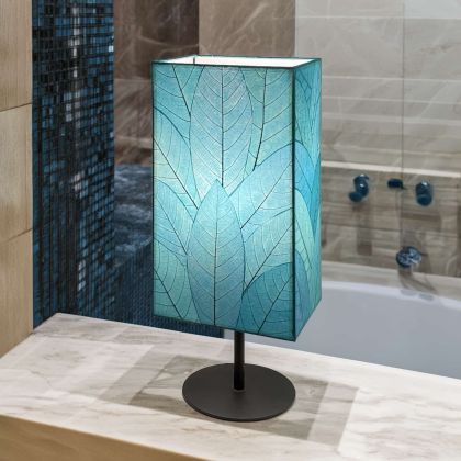 Tall Sequoia?inspired table lamp crafted by Eangee Home Design clad in sea blue fossilized cocoa leaves on a curved wrought?iron frame; towering form echoes tree bark texture, and warm light shines against the leaf?veined surface; handcrafted sustainably by fair?trade artisans
