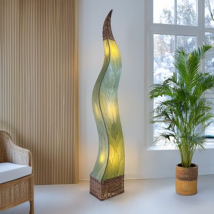 In a quiet bedside corner, crafted by the artisans of Eangee Home Design, the Flame Giant Lamp in green stands gracefully, featuring fossilized cocoa leaf shade, abaca rope accents, fair trade, adding warmth and character to the space.