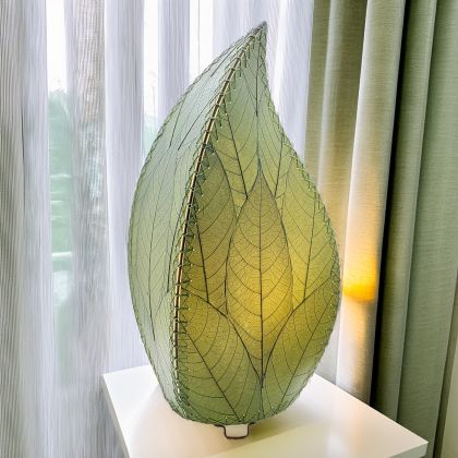 In a minimalist loft with natural textures, crafted by the artisans of Eangee Home Design, the 24 Inch Leaflet Lamp in green stands gracefully, featuring fossilized cocoa leaf shade, abaca rope accents, wrought iron frame, handcrafted, adding warmth and character to the space.