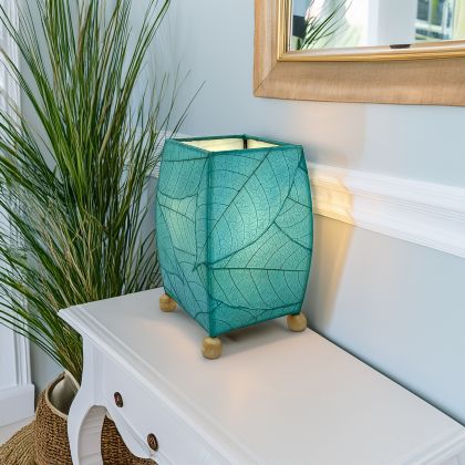 Crafted by the artisans of Eangee Home Design, the Mini Square Cocoa Leaf Table Lamp in sea blue against a clean backdrop, featuring fossilized cocoa leaf shade, wrought iron frame, fair trade, eco friendly, sustainably sourced, handcrafted.