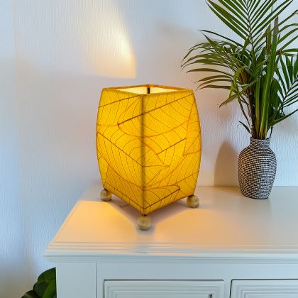 Crafted by the artisans of Eangee Home Design, the Mini Square Cocoa Leaf Table Lamp in yellow against a clean backdrop, featuring fossilized cocoa leaf shade, wrought iron frame, fair trade, eco friendly, sustainably sourced, handcrafted.