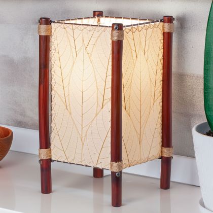 Square Fortune series table lamp crafted by Eangee Home Design wrapped in natural fossilized cocoa leaves, abaca?stitched edges, rattan legs; geometric lines softened as soothing light radiates through the natural leaf veins; sustainably handcrafted by skilled artisans
