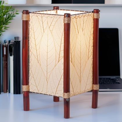In a minimalist loft with natural textures, crafted by the artisans of Eangee Home Design, the Fortune Table Lamp in natural stands gracefully, featuring fossilized cocoa leaf shade, abaca rope accents, rattan leg supports, adding warmth and character to the space.