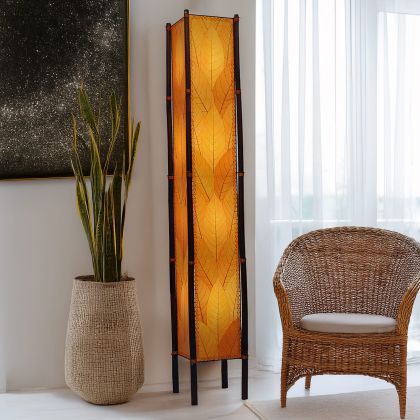 In a minimalist den with wooden accents, the Fortune Giant Floor crafted by the artisans of Eangee Home Design Lamp in orange finish by Eangee Home Design stands tall, its fossilized cocoa leaf panels, abaca twine accents, rattan legs, powder coated wrought iron frame, wrought iron frame, hand placed natural leaves, hand placed leaf panels, and abaca twine stitching casting a warm glow that some pieces don't just fill a space they define it.