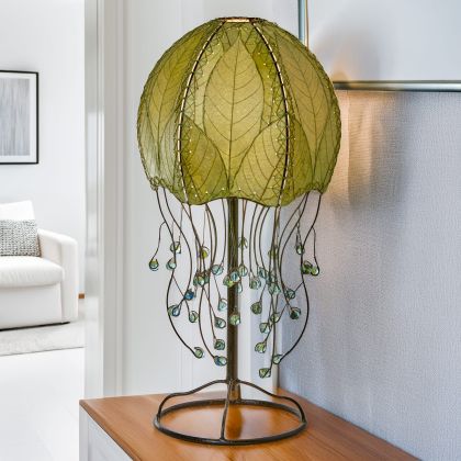 In a coastal inspired living room, crafted by the artisans of Eangee Home Design, the Jellyfish Table Lamp in green stands gracefully, featuring fossilized cocoa leaf shade, abaca rope accents, wrought iron frame, handcrafted, adding warmth and character to the space.