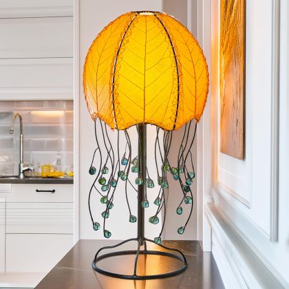 Jellyfish?inspired table lamp crafted by Eangee Home Design draped in orange cocoa?leaf panels that flow like tentacles; underwater feel enhanced as ambient light radiates through organic leaf texture; eco?friendly, artisan?crafted design