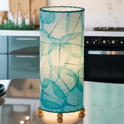 In a softly lit reading nook, crafted by the artisans of Eangee Home Design, the Banyan Table Lamp in sea blue stands gracefully, featuring wrought iron frame, eco friendly, adding warmth and character to the space.