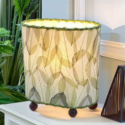 In a sun drenched entryway, crafted by the artisans of Eangee Home Design, the Mini Guyabano Table Lamp in green stands gracefully, featuring fossilized cocoa leaf shade, guyabano leaf shade, wrought iron frame, adding warmth and character to the space.