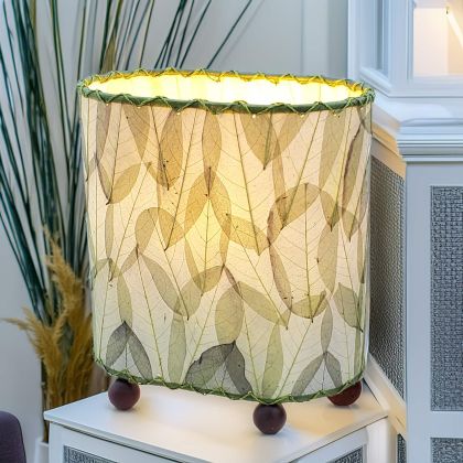 Crafted by the artisans of Eangee Home Design, the Mini Guyabano Table Lamp in green against a clean backdrop, featuring fossilized cocoa leaf shade, guyabano leaf shade, wrought iron frame.