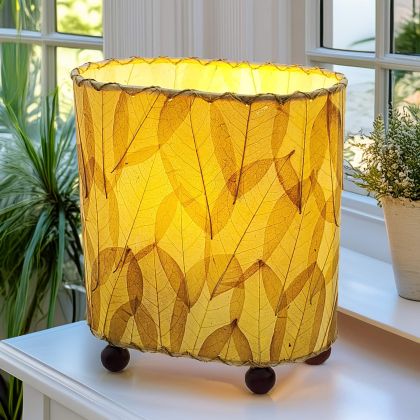 Crafted by the artisans of Eangee Home Design, the Mini Guyabano Table Lamp in natural against a clean backdrop, featuring fossilized cocoa leaf shade, guyabano leaf shade, wrought iron frame.