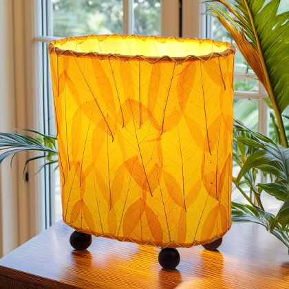 Crafted by the artisans of Eangee Home Design, the Mini Guyabano Table Lamp in orange against a clean backdrop, featuring fossilized cocoa leaf shade, guyabano leaf shade, wrought iron frame.