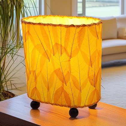 In a coastal inspired living room, crafted by the artisans of Eangee Home Design, the Mini Guyabano Table Lamp in orange stands gracefully, featuring fossilized cocoa leaf shade, guyabano leaf shade, wrought iron frame, adding warmth and character to the space.